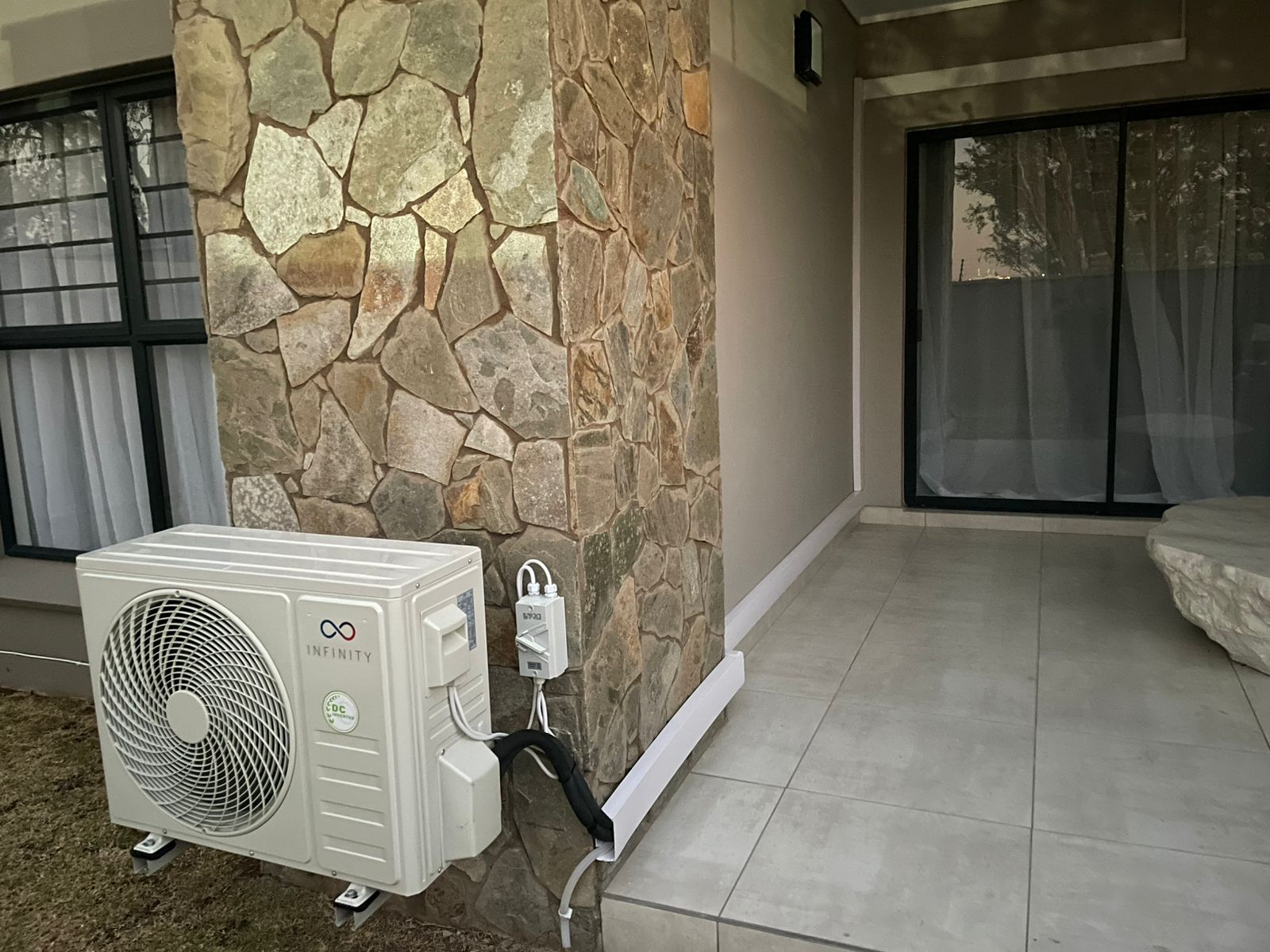 Glenntrix-installed Infinity outdoor unit on a stone-clad wall